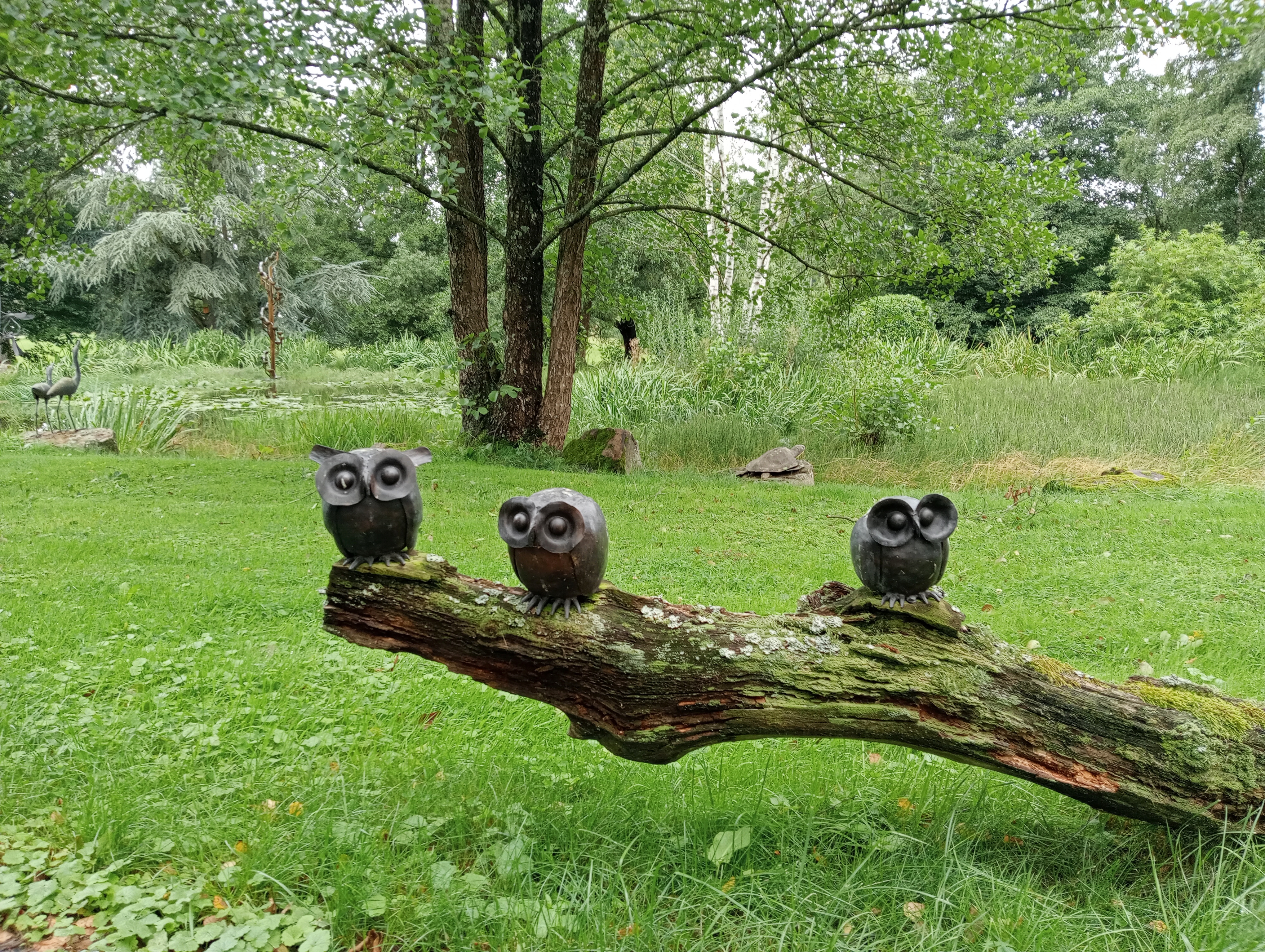 Foto van drie koperen uilen op een boomstronk. Skulpturenpark Krüft - Niederprüm