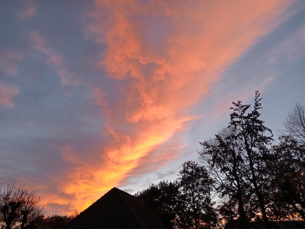 Foto van betoverende zonsondergang waarbij het blauwe wolkendek roze oranje en geel kleurt.